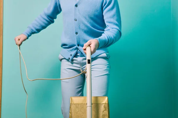 stock image Man cleaning room with vintage vacuum cleaner against turquoise wall