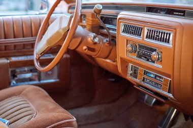 Ön panelinde sütun direksiyonu ve ahşap sütunlu klasik klasik bir arabanın içi yolcu penceresinden görülüyor.