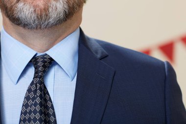 Arka planda kurdelelere karşı kravat takan sakallı zarif adamın yakın görüntüsü.