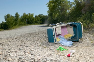Terk edilmiş bir bebek arabası ya da bebek arabası, yan yatmış bir yol kenarında çamurdan dökülen oyuncaklar, bir bebek ayakkabısı ve battaniye.