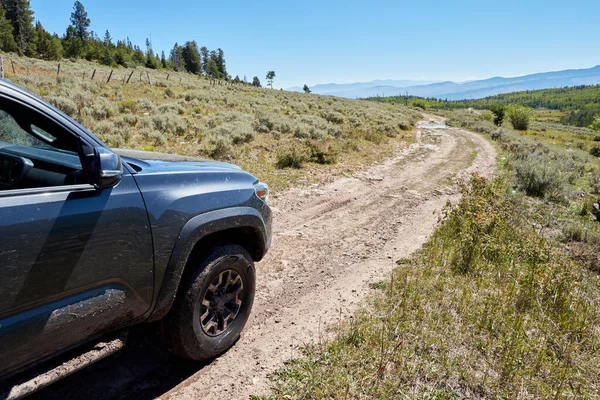 4WD aracı dar bir toprak yolda manzaralı dağ manzarası boyunca ilerliyor. Ön taraftaki yakın çekim manzarası çevreye bakıyor.