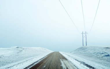 Kuzey Dakota kırsalındaki çakıl yolu karla kaplı Heart River Vadisi 'ne doğru gidiyor.