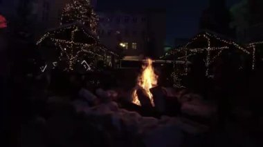 Kasaba meydanında bir Noel pazarı sallanıyor. İnsanların hediye almak için alışveriş yaptığı ışıklarla süslenmiş birkaç ahşap tezgah var. Meydanın ortasında büyük bir şenlik ateşi var.