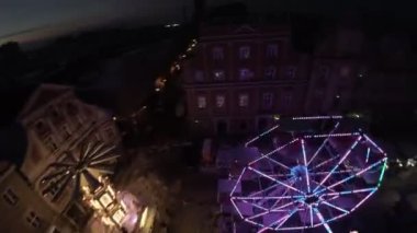 Parlak ışıkları olan güzel bir atlıkarlı atlıkarlı bir kasaba meydanının gece merkezidir. Video, meydanın havadan görüntüsüyle açılıyor ve atlıkarıncayı tüm ihtişamıyla gösteriyor. Kamera o zaman.
