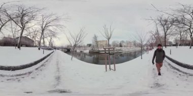 Güzel, küçük bir kasabada, sakin bir kanalın yanında, karla kaplı bir patika boyunca sakin bir yürüyüş yap. Karla kaplı ağaçlara ve donmuş nehre hayran ol ve kışın serin havasını içine çek. Hisset...