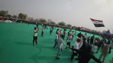 Bu büyüleyici video, Hindistan, Ahmedabad 'da canlı bir Holi kutlamasının kuşbakışı görüntüsünü sunuyor. Yeşil alan rengarenk bir isyana dönüşür şenlikler dans eder, şarkı söyler ve renkli şeyler fırlatır.