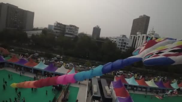 在河边广阔的绿地上举行的一个风筝节的迷人的空中景观 天空装饰着各种形状和尺寸的彩色风筝 包括一个突出的风筝 — 图库视频影像
