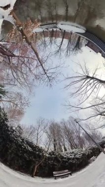 Bu 360 derecelik videoyla kışın karlı bir parkta sanal bir tura çıkın. Video, soğuk bir kış günü, karla kaplı ağaçlar ve çalılarla ve donmuş bir göletle parkın güzelliğini yakalar.
