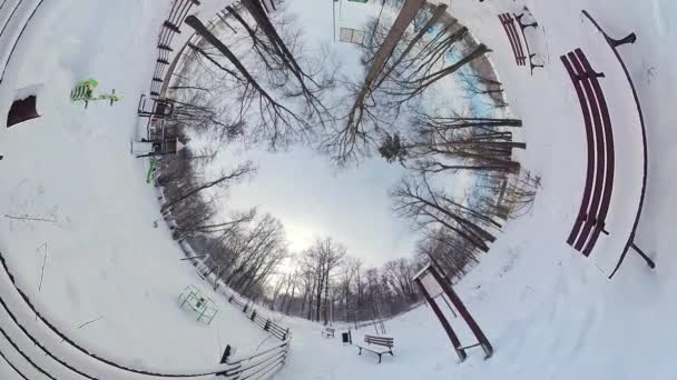 これは冬の雪の公園の360度ビデオです ビデオは 雪に覆われた木 ベンチ そしてパスを持つ公園を示しています ビデオは地面から撮影され 公園の完全な景色を提供しています — ストック動画