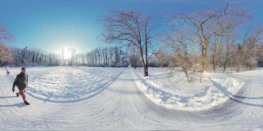 Karlı bir parkta huzurlu bir yürüyüş yap ve kışın doğanın güzelliğinin tadını çıkar. Video 360 derece, böylece etrafa bakabilir ve karla kaplı ağaçları, çalıları ve açık alanları görebilirsiniz. Şey...