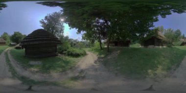 Bu 360 derecelik video geleneksel bir Ukrayna köyünü gösteriyor. Birkaç sazdan çatı evi ve toprak bir yol var. Video güneşli bir günde çekildi ve her yerde ağaçlar ve yeşillikler var.