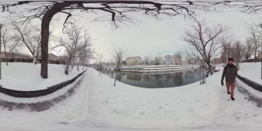 Karla kaplı bir patika boyunca şehrin göbeğindeki donmuş bir kanalın yanında sanal bir gezinti yapın. Karla kaplı ağaçlara ve binalara hayranlık duyun ve giderken serin kış havasını hissedin..