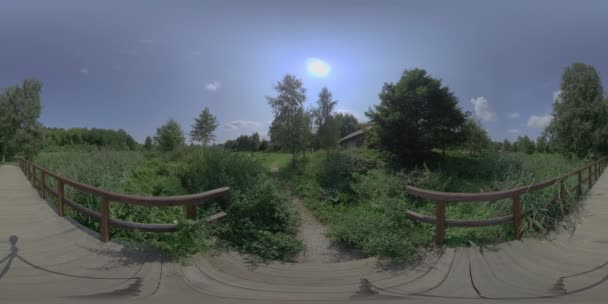 这是一个360度的视频 是在阳光灿烂的一天 在森林里的一座木制人行天桥 视频一开始是从正面看到桥的 这座桥是木制的 两边都有栏杆 — 图库视频影像
