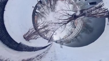 Bu, karlı bir parkın 360 derecelik bir videosu. Videoda parkın ortasında, sağında bir bank olan çıplak bir ağaç görülüyor. Zemin karla kaplı ve karda ayak izleri var.