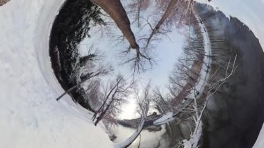 Bu 360 derecelik videoda sakin bir kış manzarasında büyüleyici bir yolculuğa çıkın. Çekilen görüntüler sizi karla kaplı ağaçlar ve donmuş bir nehrin olduğu sakin bir ormana götürüyor.