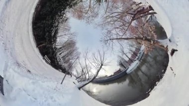 Bu büyüleyici videoda sakin bir kış manzarası boyunca büyüleyici bir yolculuğa çıkın. Sahne, kalın bir battaniyeye sarılı, karla kaplı bir nehir yatağının nefes kesici panoramik görüntüsüyle başlıyor.