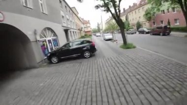 Video, sokağın sürücülerin bakış açısıyla başlıyor. Cadde apartmanlarla dolu ve caddenin her iki tarafında park edilmiş arabalar var. Şoför geliyor.