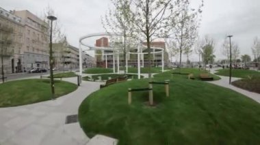 Bu video, Polonya 'nın Opole kentinde yeni tamamlanmış bir şehir parkını gösteriyor. Park, çimen tepecikleri, beton yollar ve stratejik olarak yerleştirilmiş banklarla modern peyzaja sahiptir. Öyle.