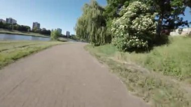 Bu yürüyüş yolu olan güzel bir nehir kenarı parkının videosu. Park bir şehirde yer almaktadır ve ağaçlar, çalılar ve çiçeklerle çevrilidir. Yol tuğladan yapılmış ve banklarla kaplı.