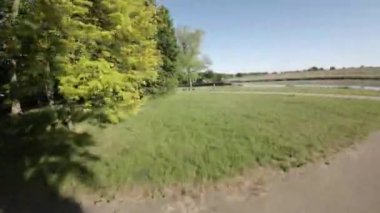 Bu, yemyeşil yemyeşil ve huzurlu bir nehri olan güzel bir parkın videosu. Park uzun ağaçlar, yeşil çimenler ve renkli çiçeklerle dolu. Nehir sakin ve sakin, ve nehirden akıyor.