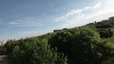 Bu video yeşil ağaçların ve çimenli alanların bol olduğu güzel bir parkı gösteriyor. Yürümek, koşmak ve bisiklete binmek için mükemmel olan asfalt yollar ağına sahiptir. Park yeri belli.