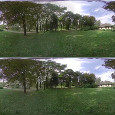 Bu güzel yeşil bir parkın 360 derecelik panoramik videosu. Video, yemyeşil çimenler ve birkaç ağacın bulunduğu geniş ve açık bir alan gösteriyor. Uzakta, küçük bir ev var. Gökyüzü mavi
