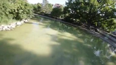 Videoda parkta bir çeşme var. Çeşme yuvarlaktır ve çeşitli katları vardır. Su fıskiyeleri havaya fırlıyor ve çeşmeye geri düşüyor. Çeşme ağaçlarla çevrili ve...
