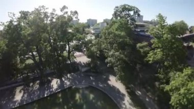 Video bir parkın havadan görüntüsüyle başlıyor. Park yemyeşil ağaçlar ve köpüklü bir çeşmeyle dolu. Çeşme bir yürüyüş yolu ile çevrili ve yakınlarda birkaç bank var.