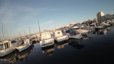 Bu büyüleyici video, bir dizi tekne ve yatla dolu pitoresk bir limanı gösteriyor. Sakin sular bu gemiler için bir sığınaktır, boyut ve stil olarak gösterişli ve modern olandan