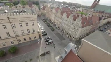 Polonya 'nın eski Varşova kasabasında dar bir cadde. Cadde, çoğu restore edilmiş olan eski binalarla dolu. Binaların önünde birkaç ağaç ve birkaç açık hava koltuğu var.