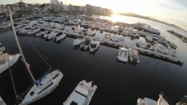 Video günbatımında huzurlu bir İspanyol limanının geniş açılışıyla başlıyor. Gökyüzünün sıcak renkleri ve sakin su rahatlatıcı ve sakin bir atmosfer yaratır. Kamera sonra sola döner.