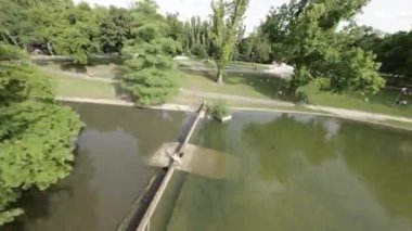 Budapeşte, Macaristan 'da bir parkta yürüyüşün birinci şahıs bakış açısı videosu. Video güneşli bir günde çekiliyor ve bir göl, bir heykel ve bir oyun alanı gibi çeşitli sahneleri gösteriyor. Şey...