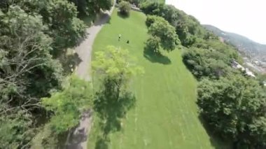 Güneş gözlüklü ve beyaz gömlekli genç bir adam çimenli bir tepede parkur yapıyor. Tepeye doğru koşmaya başlıyor, sonra ters takla atıyor ve koşmaya devam ediyor. Daha sonra başka parkçılar da yapıyor.