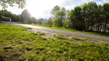 Paten kayanların güzel bir parka bakış açısı. Video, yemyeşil ağaçları, açık çimenli alanları ve parkın tadını çıkaran birkaç kişiyi gösteren pürüzsüz, birinci şahıs sürüşü. Şey...