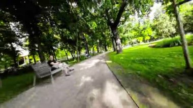 Polonya 'nın Opole kentindeki yemyeşil bir parkta huzur verici bir yürüyüş. Park çeşitli ağaçlar, çimenlik alanlar ve güzel günün tadını çıkaran birkaç insanla dolu. Rahatlamak ve kaçmak için mükemmel bir yer.
