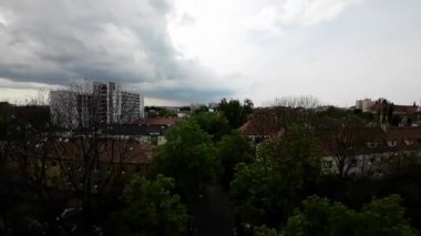 Burası her iki tarafında ağaçlar ve binalar olan bir yerleşim yeri. Cadde kaldırım taşından yapılmıştır ve her iki tarafında kaldırımlar vardır. Ağaçlar yapraklarla dolu ve gökyüzü bulutlu.
