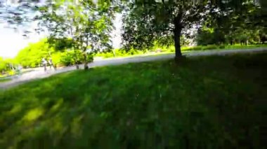 Paten kayanların güzel bir parka bakış açısı. Video, izleyiciyi parkta bir yolculuğa çıkaran pürüzsüz ve kesintisiz bir çekim. Patenci ağaçların, çiçeklerin ve göletin yanından geçiyor.