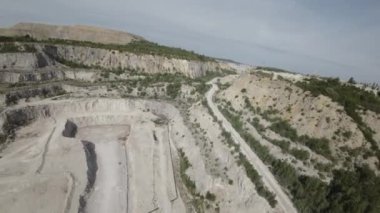 Bu video, bir kireçtaşı ocağının havadan görüntüsünü sağlıyor. Taş ocağı kırsal bir alanda yer almaktadır ve etrafı ağaçlar ve tarlalarla çevrilidir. Taş ocağı suyla dolu..