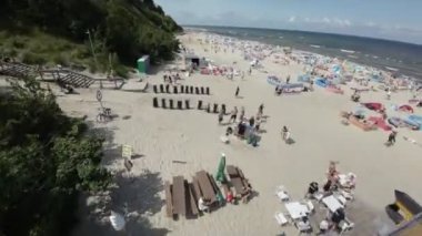 Polonya 'nın Jastrzebia Gora sahilinde güzel bir yaz günü. Sahil güneşin ve suyun tadını çıkaran insanlarla dolu. Sahilde bir sürü renkli şemsiye ve çadır var. Su...