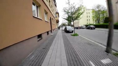 Video, sürücünün direksiyondaki elinin görüntüsüyle başlıyor. Araba dar bir sokaktan geçiyor, her iki tarafında ağaçlar var. Cadde eski binalarla dolu. Birkaç araba var.