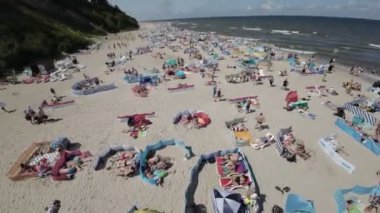 Video, Polonya 'nın Jastrzebia Gora kentindeki bir plajın çarpıcı hava manzarasını içeriyor. Sahil sıcak yaz güneşi ve serin Baltık Denizi 'nin tadını çıkaran insanlarla dolu. Açık mavi su mükemmel.