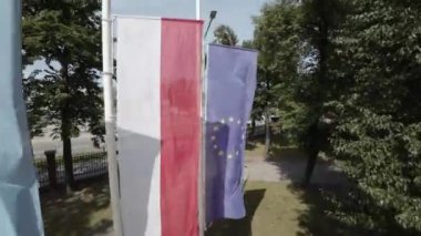 Video rüzgarda dalgalanan üç bayrak gösteriyor. İlk bayrak, 12 sarı yıldızlı mavi bir bayrak olan Avrupa Birliği bayrağı. İkinci bayrak Polonya bayrağı, beyaz ve