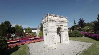 Video, parkta bulunan Zafer Takı 'nın minyatürünü gösteriyor. Minyatür beyaz taştan yapılmıştır ve renkli çiçekler ve yeşil otlarla çevrilidir. Video alçak bir açıdan çekilmiş.