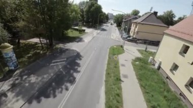 Video, kalabalık bir caddenin, arabaların ve kaldırımda yürüyen insanların görüntüsüyle başlıyor. Kamera daha sonra sağa dönerek apartman ve evlerin olduğu bir yerleşim alanı gösteriyor. Şey...