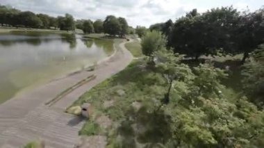 Kendinizi doğanın dingin güzelliğine bu büyüleyici videoyla daldırın. Kameramız sizi çarpıcı bir parka doğru sakin bir yolculuğa çıkarıyor. Tahta bir sahil yolu boyunca süzülüyor.