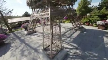 Bu, Eyfel Kulesi olan güzel bir bahçenin videosu. Bahçede güller, zambaklar ve laleler dahil olmak üzere birçok farklı çiçekler vardır. Üzerinde köprü olan bir gölet var ve birkaç tane de var.