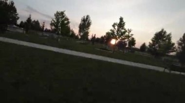 Video, gün batımında bir parkın FPV insansız hava aracı görüntüsüyle başlıyor. İnsansız hava aracı birkaç ağaç ve çalıyla geniş bir otlak üzerinde uçuyor. Arka planda bir yol ve bir çit var.