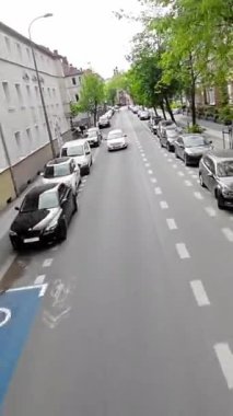 Bu, her iki tarafında arabaların park edildiği bir yerleşim yeri sokağının videosu. Video, caddede araba kullanan bir sürücünün perspektifinden çekildi. Sokaklar ağaçlarla dolu.