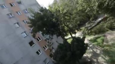 Bu parkta bir yürüyüşün videosu. Video, yüksek bir apartman manzarası ile başlıyor. Kamera daha sonra bir sürü ağaç ve çalıyla dolu bir parkı göstermek için sağa döner. Bir yol var.
