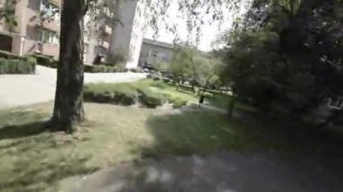 Video, büyük bir şehrin ortasındaki küçük bir parkın üzerinde uçan bir İHA 'nın FP V görüntüsüyle başlıyor. İnsansız hava aracı ağaçlar ve çiçeklerle kaplı bir patikanın üzerinde uçuyor.